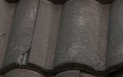 Cracked concrete roof tile in a weathered tile course